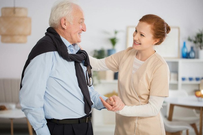 Caregiver holding elderly man's hand.