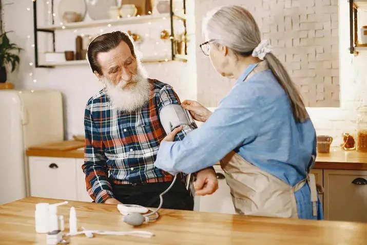 Nurse checking elderly man's blood pressure